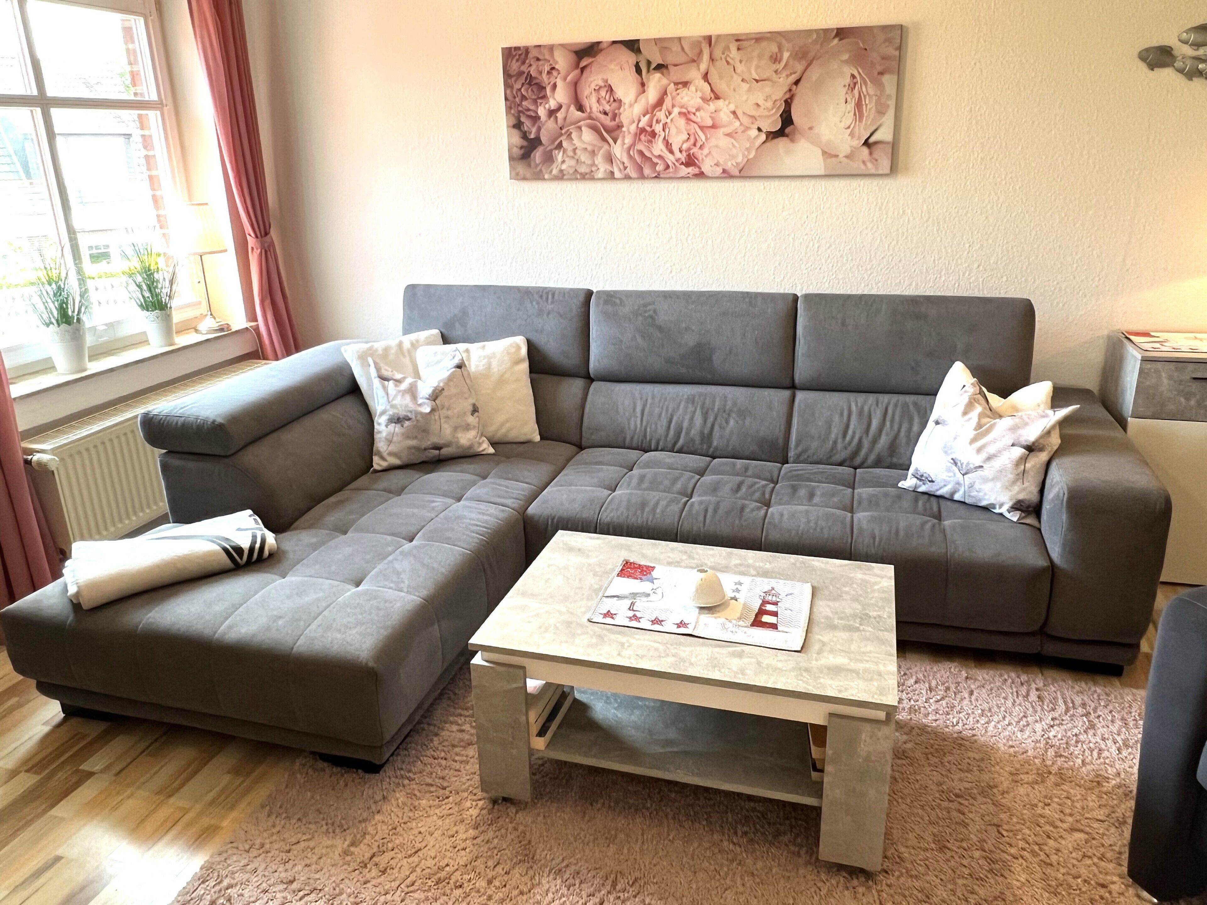 Un soggiorno con un divano modulare grigio, un tavolino da caffè e un quadro floreale appeso alla parete.