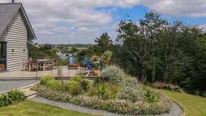 Ein Haus mit Terrasse, Sitzgelegenheiten im Freien und einem Garten.