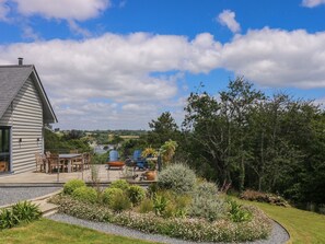 Ein Haus mit Terrasse, Sitzgelegenheiten im Freien und einem Garten.