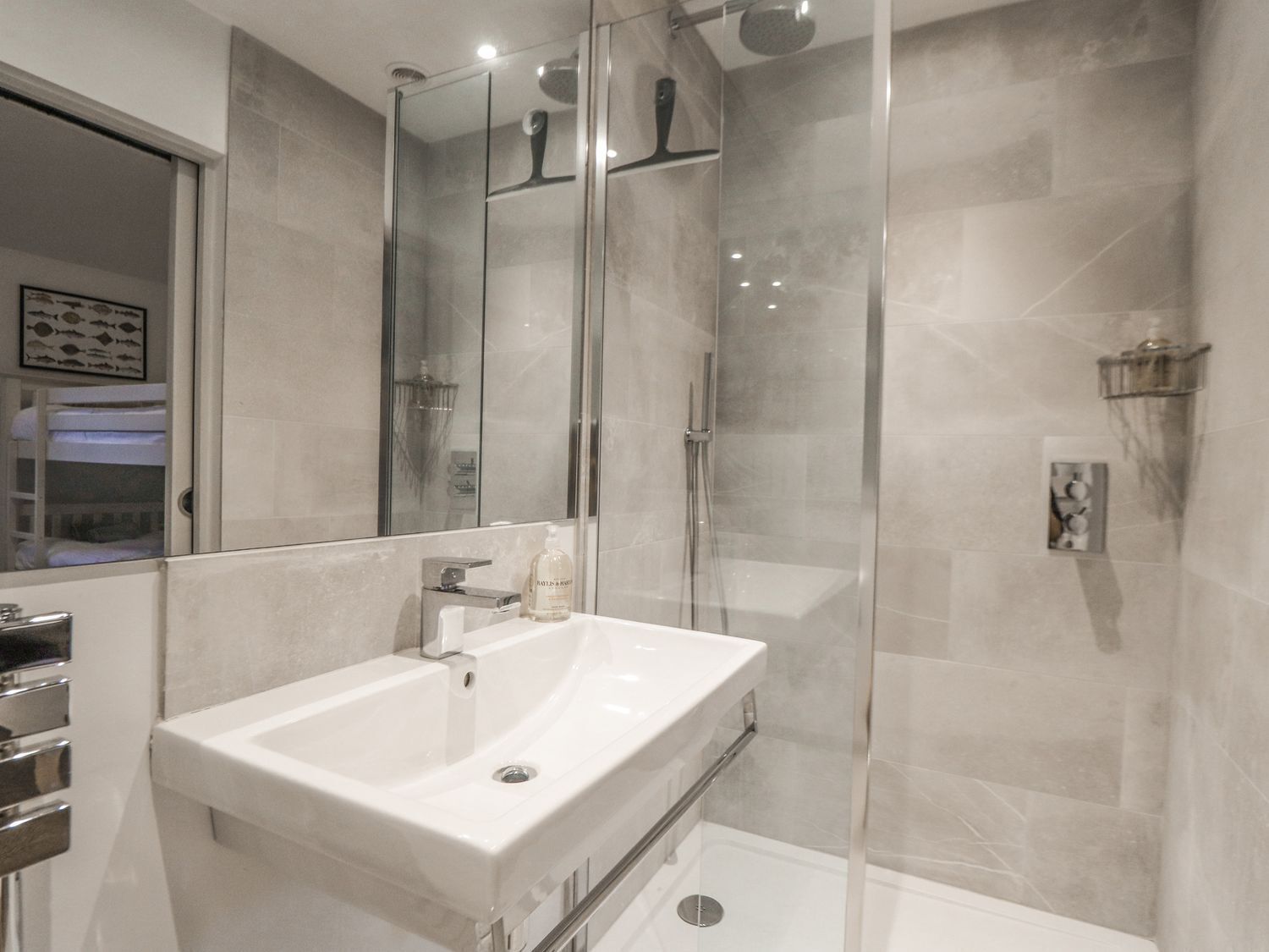 A modern bathroom with a glass-enclosed shower, a white sink, and a mirror.