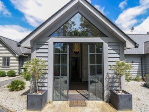 A modern house with a large glass door entrance, a sloped roof, and a small porch area. - Wood Meadow (Helston)