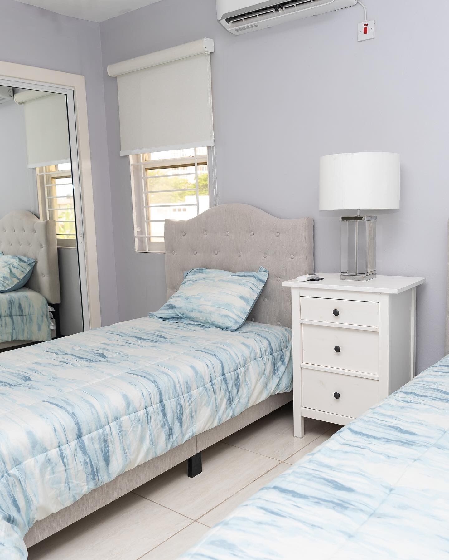 A bedroom with a bed, bedside table, lamp, and window with blinds.