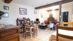 Een gezellige woonkamer met een open haard, een boekenkast, een eettafel en een bank.