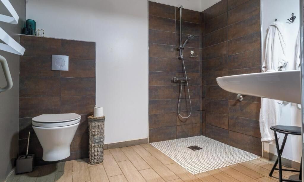 A modern bathroom with a shower, toilet, and sink.