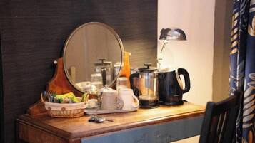 Une table en bois, un miroir, une machine à café, une bouilloire et une lampe.