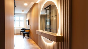 A hallway with a wooden panel wall, a built-in bench, and a large mirror. - Grodzka Apartments (Jelenia Góra)