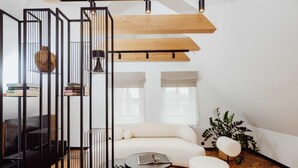 A modern living room with a sofa, a coffee table, a black TV stand, and a bookshelf. - Grodzka Apartments (Jelenia Góra)