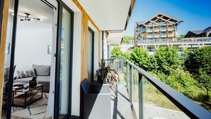 A balcony with a sofa, a coffee table, and a potted plant. - Grodzka Apartments (Jelenia Góra)