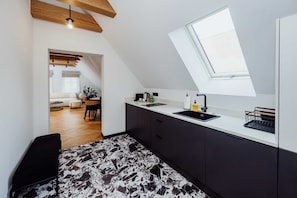A modern kitchen with a skylight, dark cabinets, and a black and white patterned floor.