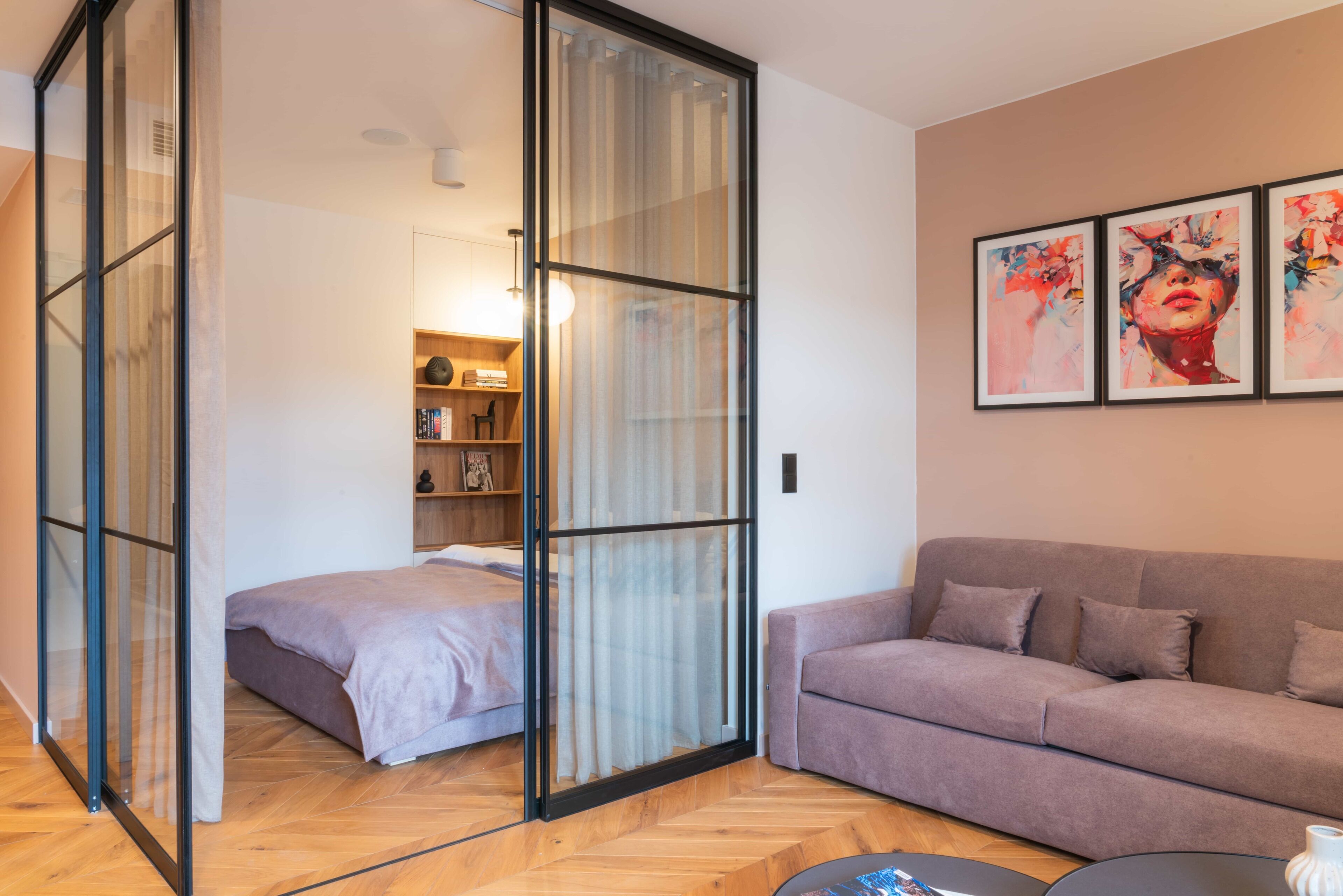 A modern living room with a sofa, a coffee table, and a bed with a sliding glass door.