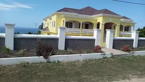 A two-story yellow house with a red roof, white columns, and a balcony. - Kingsbird By The Sea- Cozy 1 Bedroom (Runaway Bay)