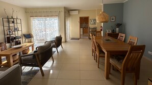 Amplia sala de estar con una mesa de comedor, sillas, una estantería y un ventanal con vistas.