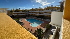 Un edificio residencial con piscina, balcones y cielo despejado.