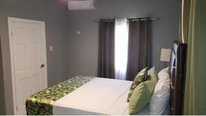 Ein Schlafzimmer mit Bett, Vorhängen, einer Tür und einer Klimaanlage.