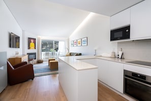 A modern kitchen with a central island, white cabinetry, and a built-in microwave. - Quinta do Lago Charming Apartment (S53) (Quinta do Lago)