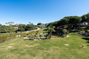 A well-maintained grassy area with a curved pathway, a small pond, and trees. - Quinta do Lago Charming Apartment (S53) (Quinta do Lago)