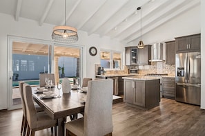 A modern kitchen with a central island, stainless steel appliances, and a dining area with a table and chairs. - Exquisite Villa ~ 3 mins to beach w/ pool (Noord)