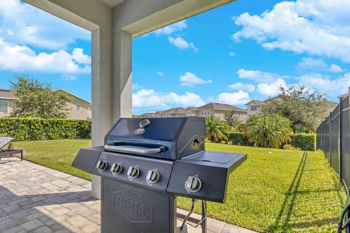 A barbecue grill with four burners, a control panel, and a logo.
