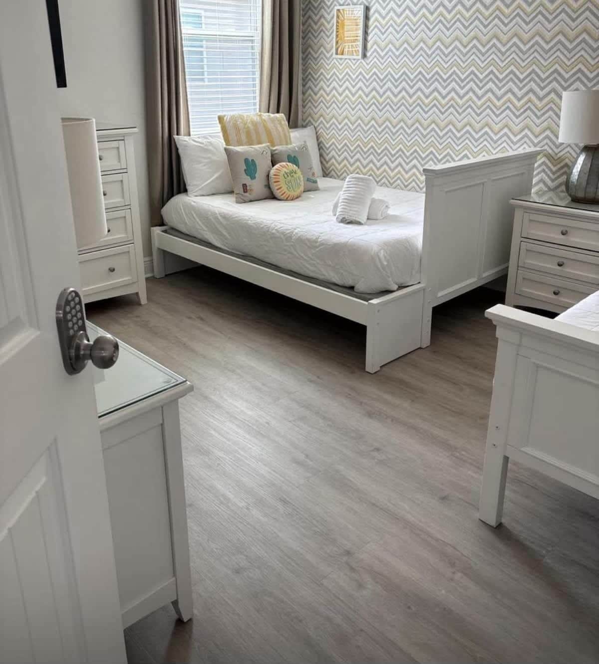 A bedroom with a bed, bedside tables, a dresser, a mirror, and a window with curtains.