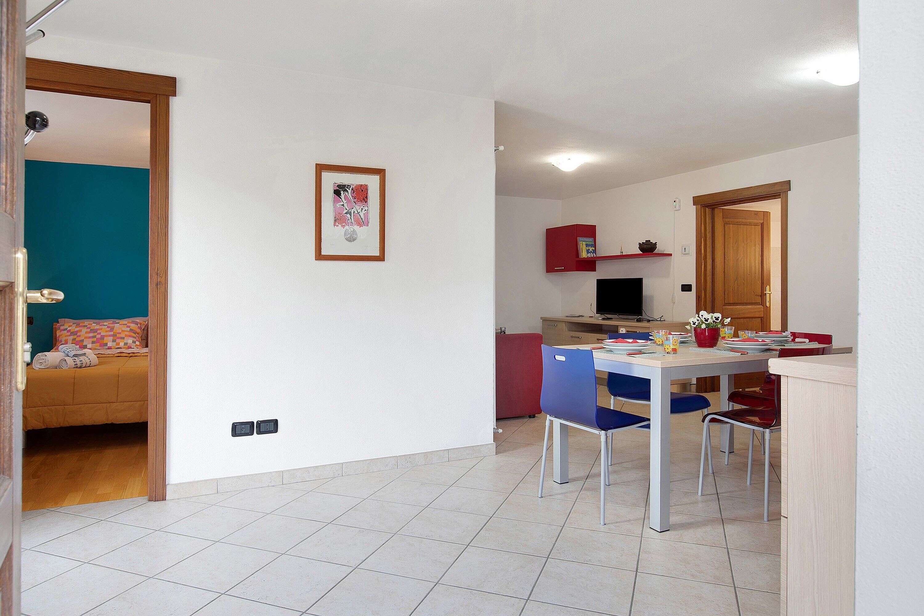 Une pièce comprenant un lit, une table à manger avec des chaises, un coin cuisine et une porte donnant sur une autre pièce.