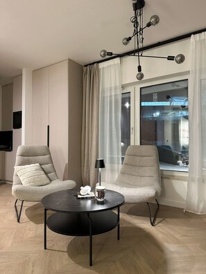 A modern living room with two armchairs, a round coffee table, a lamp, and a large window with curtains. - Pine Apartments - Dolina Szczęścia (Szklarska Poręba)