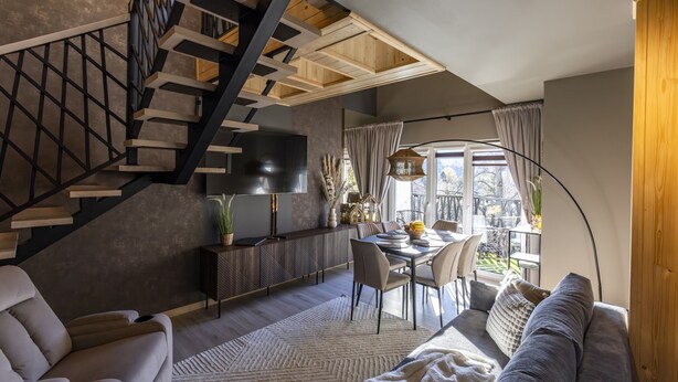 Un salon moderne avec un escalier, un coin repas et une grande fenêtre avec des rideaux.