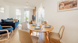 Un salon moderne avec une table à manger pour quatre personnes, un canapé et un téléviseur.
