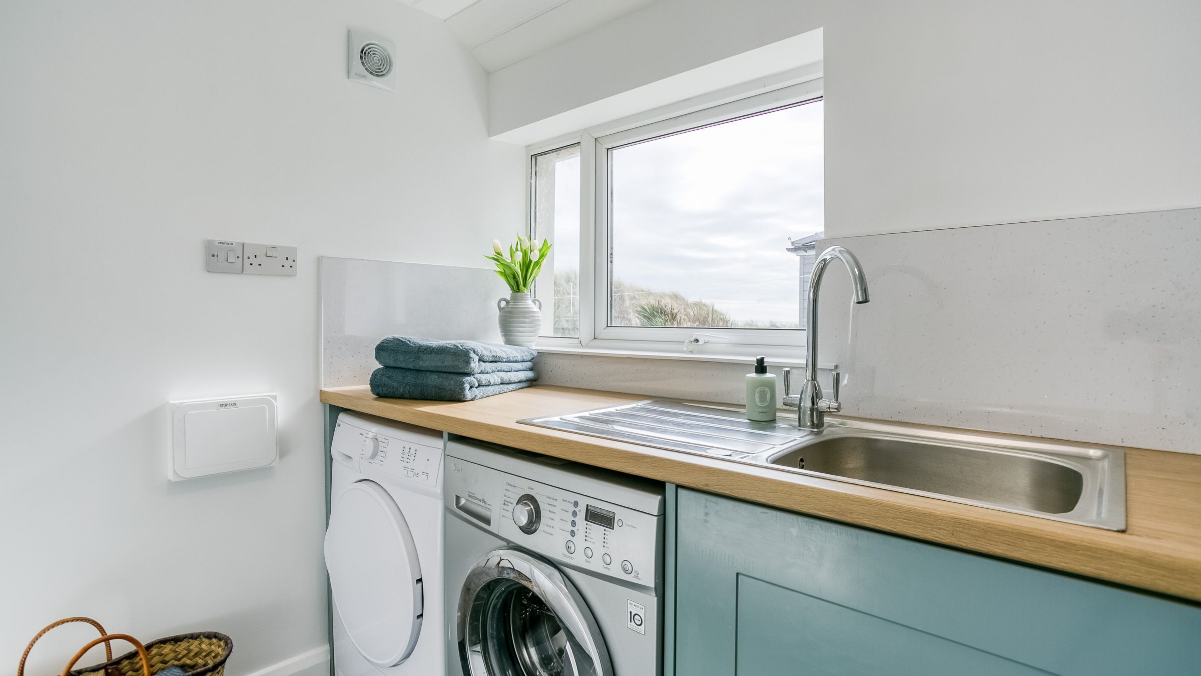 A compact kitchen with a washing machine, a sink, and a window.