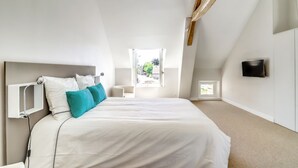 Un dormitorio con una cama grande, un televisor montado en la pared y una ventana que ofrece vistas al exterior.