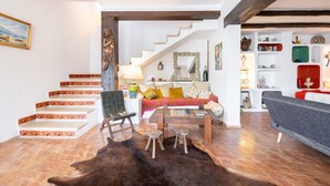 A living room with a staircase, a sofa, a coffee table, and a rug.
