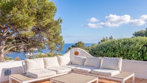 A white outdoor seating area with a view of the sea.