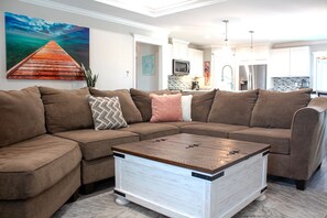 A spacious living area with a brown sectional couch opens toward the kitchen. - The Rusty Pelican -Boat-Jet ski parking available (Mexico Beach)