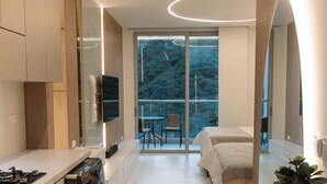 A modern kitchen with a built-in washer, a dining area with a table and chairs, and a bedroom with a bed and a large window. - Edificio Delventto cerca a la Playa Cabo Tortuga (Santa Marta)