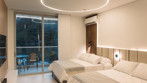 A modern bedroom with two beds, a TV, and a balcony with a glass door. - Edificio Delventto cerca a la Playa Cabo Tortuga (Santa Marta)
