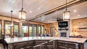 Une cuisine spacieuse dotée d’un grand îlot central, de meubles en bois et de luminaires suspendus.
