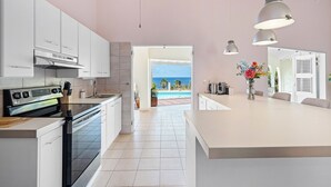 Cozinha moderna com armários brancos, forno LG e vista para a piscina e oceano.