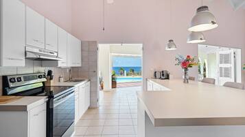 Een moderne keuken met witte kastjes, een LG-oven, en uitzicht op het zwembad en de oceaan.