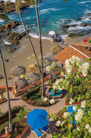 A coastal resort with a beach, palm trees, and a boat. - Oceanfront 1BR Condo | Balcony, Pool & Restaurant (Puerto Vallarta)