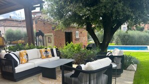 Eine Außenveranda mit einer Sitzecke, Sofas, Sesseln und einem Couchtisch.