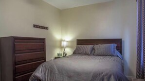 A bedroom with a bed, a nightstand, a lamp, and a dresser. - NFL Draft week 3 Bedroom Bloomfield 10 minutes to Acrisure 3 parking spaces (Pittsburgh)