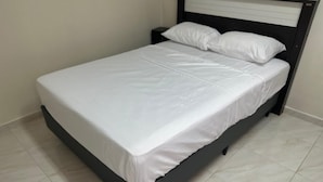 A single bed with a white mattress and pillows, a dark frame, and a tiled floor. - Aeroconforto Residential - Near the Airport and Factories in Tarumã - Room 2 (Manaus)