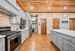 Cocina moderna con electrodomésticos de acero inoxidable, techo de madera y un letrero que dice 'happy place'.