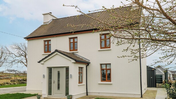 Een huis met twee verdiepingen, met een witte gevel, pannendak en een voordeur met klein voortuintje.