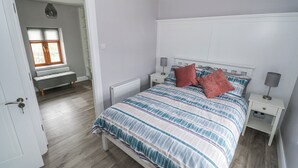 Een slaapkamer met een bed, nachtkastjes, een raam en een deur.