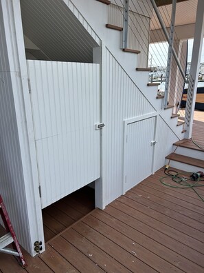Une terrasse en bois avec une porte blanche et un escalier menant à un niveau supérieur.