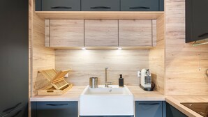 Une cuisine moderne avec un évier blanc, des meubles de couleur foncée et des éléments décoratifs en bois.