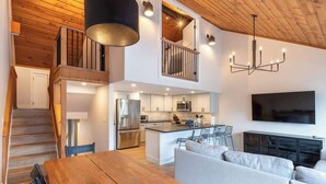 Et moderne køkken med en central ø, et spiseområde med et træbord og et opholdsområde med en sofa.
