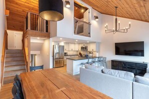 Et moderne køkken med en central ø, et spiseområde med et træbord og et opholdsområde med en sofa.