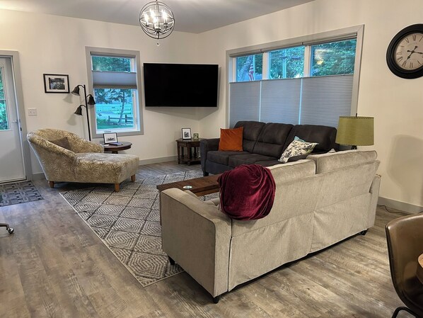 A living room with a sofa, armchair, and a flat-screen TV.