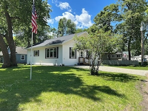 A single-story house with a front porch, a small lawn, and an American flag.